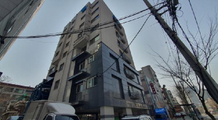 다세대주택 외관 — 아래에서 올려다본 회색 외벽의 건물 정면