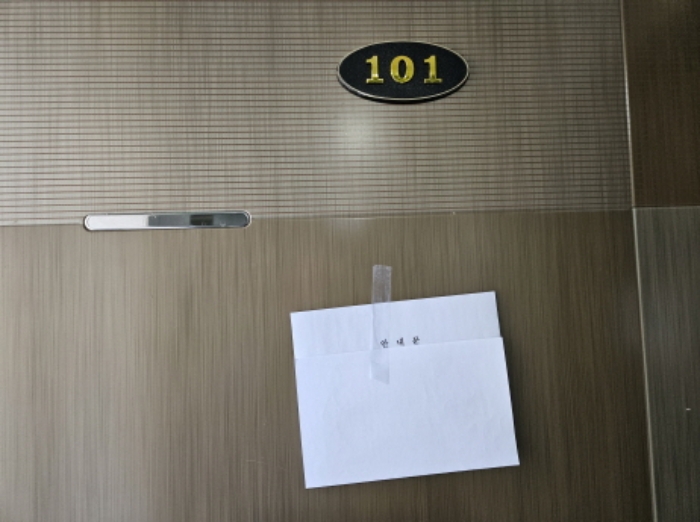 사건 2024타경12315 건물 1층 101호 현관문. 호수 표지와 법원 안내문이 붙어 있다.